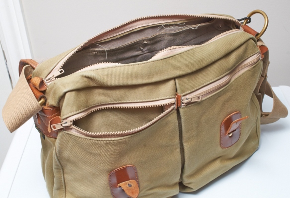 Non-adjustable straps to close the main flap. Zippers on both front pockets and main compartment